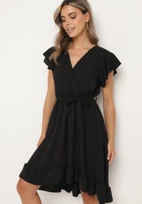 Born2be - Czarna Kopertowa Sukienka z Asymetrycznym Dołem Ozdobiona Falbanką z Paskiem w Talii Snidia. Okazja: na spacer, na co dzień. Kolor: czarny. Wzór: aplikacja. Sezon: lato. Typ sukienki: asymetryczne, kopertowe. Styl: klasyczny, casual, elegancki #4