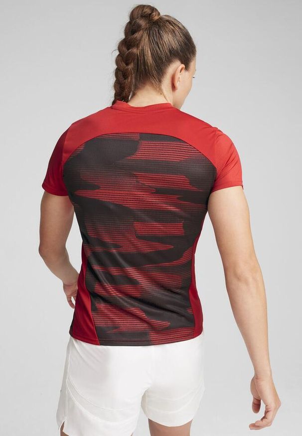 Puma - Damska koszulka przedmeczowa z krótkim rękawem AC Milan PUMA. Kolor: czerwony, czarny, wielokolorowy. Długość rękawa: krótki rękaw. Długość: krótkie