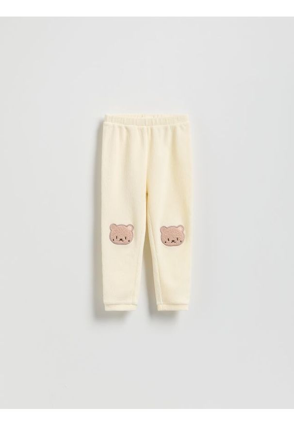 Reserved - Prążkowane legginsy z naszywką - złamana biel. Materiał: prążkowany. Wzór: aplikacja