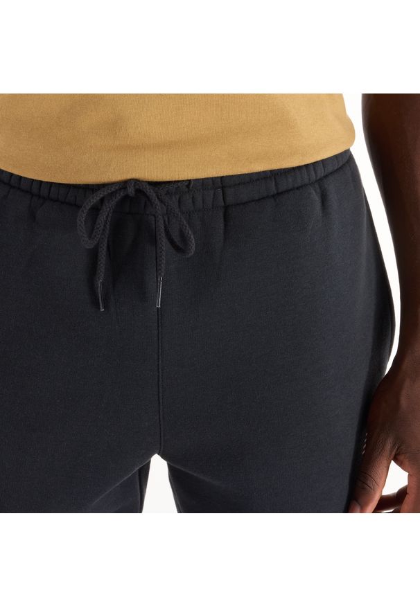 Spodnie męskie New Balance MP43904BK – czarne. Kolor: czarny. Materiał: poliester, bawełna, dresówka