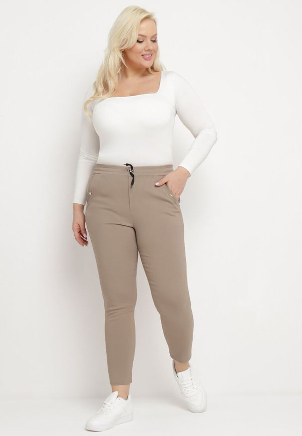 Born2be - Ciemnobeżowe Spodnie z Nogawkami 7/8 i Kieszeniami Gavotta. Okazja: na co dzień. Kolekcja: plus size. Kolor: beżowy. Materiał: satyna. Styl: elegancki, casual
