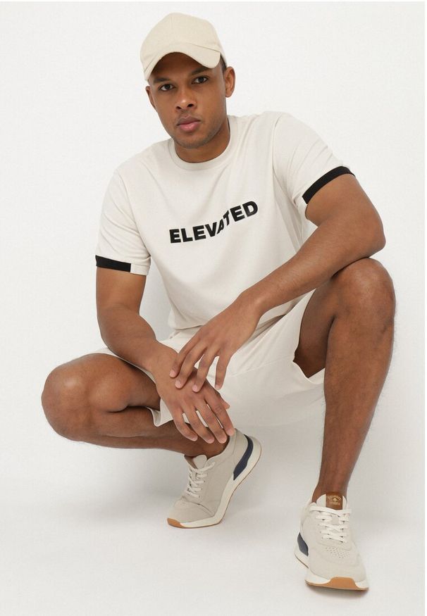 Born2be - Jasnobeżowa Koszulka T-shirt z Napisem ELAVATED Kolianis. Okazja: na co dzień. Kolor: beżowy. Wzór: napisy. Styl: klasyczny, casual