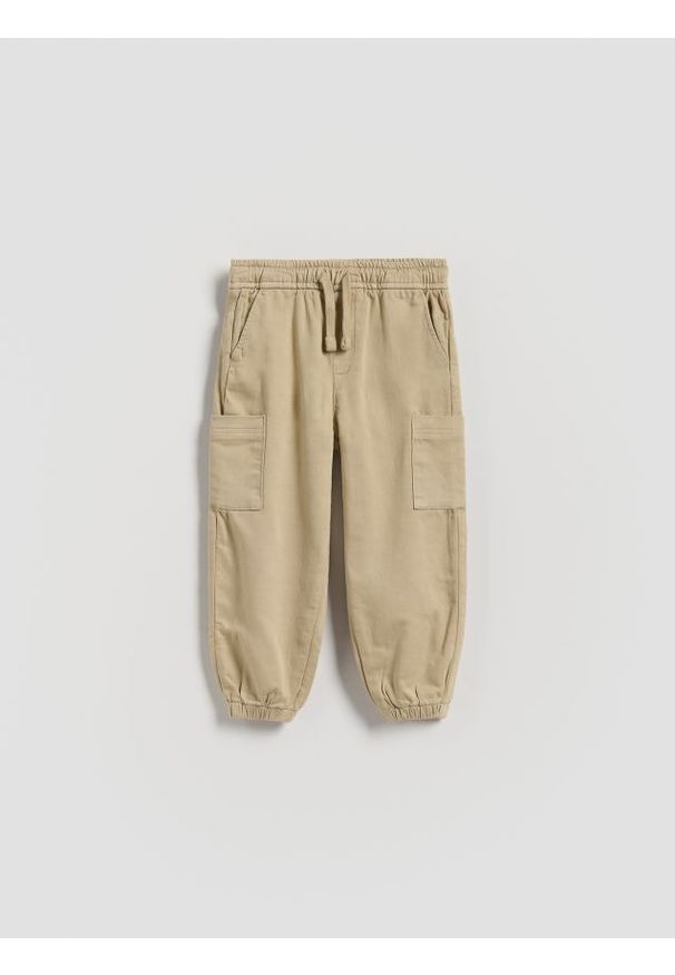 Reserved - Wysokoelastyczne joggery cargo - beżowy. Kolor: beżowy. Materiał: bawełna, tkanina