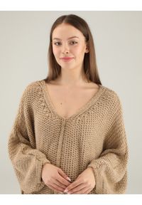 Unisono - BEŻOWY SWETER OVERSIZE. Typ kołnierza: dekolt w serek. Kolor: beżowy. Materiał: dzianina, prążkowany. Długość rękawa: długi rękaw. Długość: długie. Wzór: ze splotem