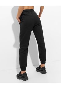 JOANNA MUZYK - Czarne spodnie dresowe z różowym logo. Stan: obniżony. Kolor: czarny. Materiał: dresówka