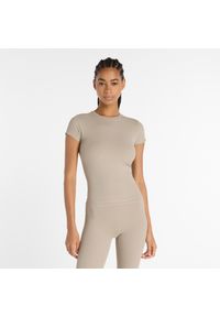 Koszulka damska New Balance WT53125ADS – beżowa. Kolor: beżowy. Materiał: poliester, materiał, prążkowany. Wzór: aplikacja. Sport: joga i pilates, fitness