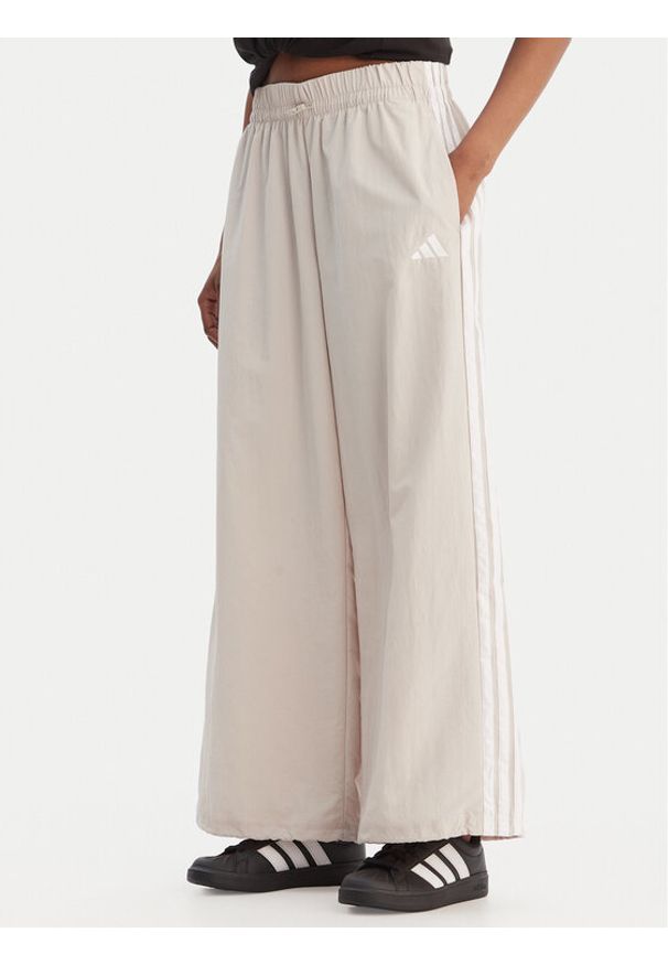 Adidas - adidas Spodnie dresowe Essentials 3-Stripes JC8168 Beżowy Loose Fit. Kolor: beżowy. Materiał: syntetyk