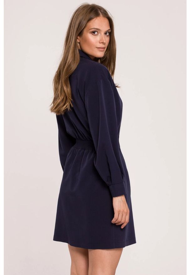 Sukienki.shop - Elegancka sukienka żakietowa dwurzędowa granatowa mini. Okazja: na spotkanie biznesowe. Typ kołnierza: dekolt kopertowy. Kolor: niebieski. Materiał: guma. Typ sukienki: kopertowe. Styl: elegancki. Długość: mini