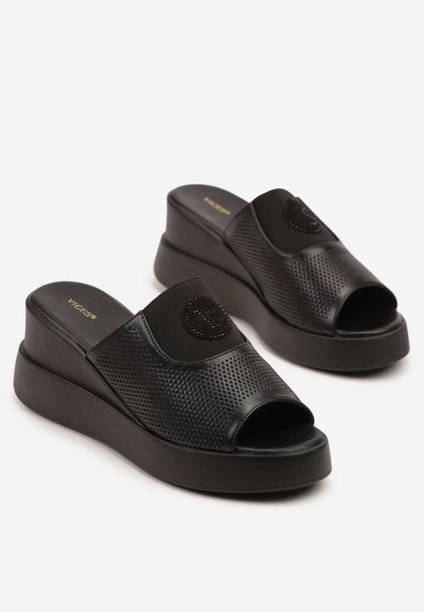 Renee - Czarne Klapki Vices na Koturnie Ozdobione Perforacją Mevirella. Okazja: na spacer, na imprezę. Kolor: czarny. Wzór: aplikacja. Sezon: lato. Obcas: na koturnie. Styl: elegancki