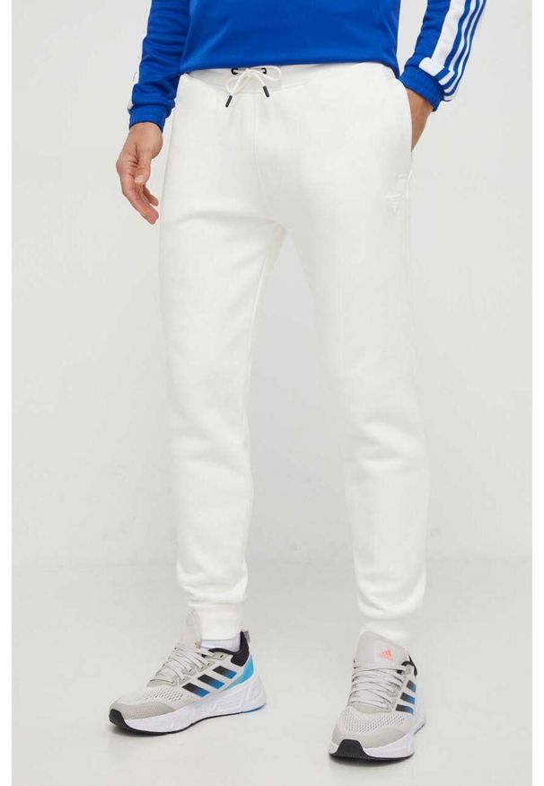 Guess spodnie dresowe kolor biały melanżowe. Kolor: biały. Materiał: dresówka. Wzór: melanż