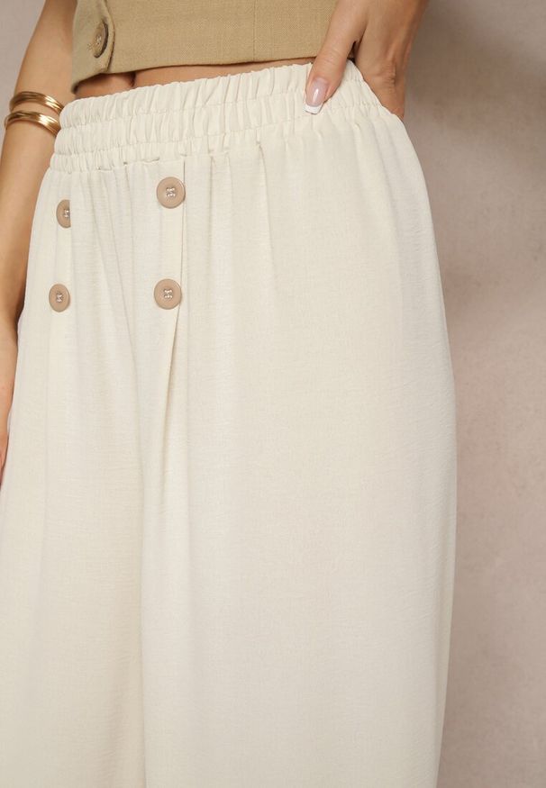 Renee - Jasnobeżowe Spodnie z Bawełną o Szerokim Kroju High Waist Ozdobione Guzikami Morritia. Okazja: na co dzień. Stan: podwyższony. Kolor: beżowy. Materiał: bawełna. Wzór: aplikacja. Styl: elegancki, casual