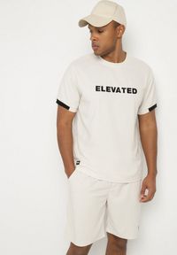 Born2be - Jasnobeżowa Koszulka T-shirt z Napisem ELAVATED Kolianis. Okazja: na co dzień. Kolor: beżowy. Wzór: napisy. Styl: klasyczny, casual
