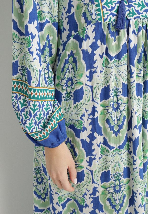 Born2be - Niebiesko-Zielona Sukienka o Rozkloszowanym Kroju z Wiązaniem z Frędzlami w Etniczny Wzór Ridalea. Okazja: na co dzień. Typ kołnierza: dekolt w serek. Kolor: niebieski. Materiał: skóra. Długość rękawa: długi rękaw. Styl: casual, elegancki, boho