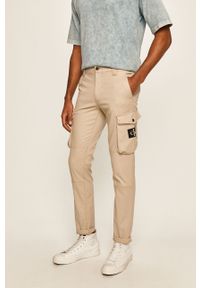 Calvin Klein Jeans - Spodnie. Kolor: beżowy. Materiał: tkanina, bawełna, elastan. Wzór: gładki #1