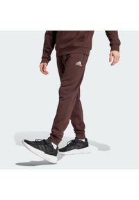 Adidas - Spodnie dresowe męskie adidas Stadium Badge of Sport. Kolor: brązowy, biały, wielokolorowy. Materiał: dresówka. Sport: taniec, joga i pilates #1