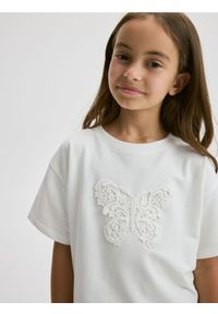 Reserved - T-shirt z naszywką - złamana biel. Materiał: bawełna. Wzór: aplikacja