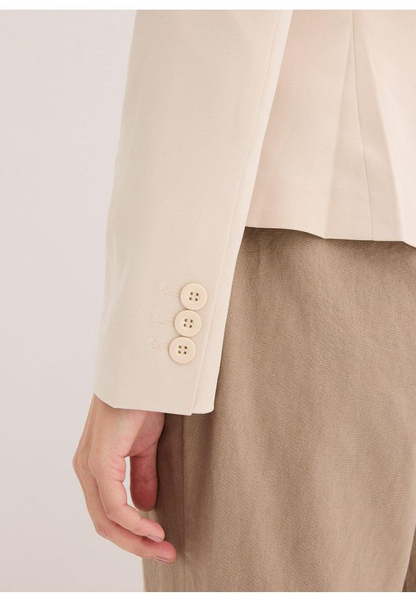 bonprix - Krótki żakiet z kieszeniami z patkami. Okazja: na spotkanie biznesowe. Kolor: beżowy. Długość: krótkie. Styl: biznesowy