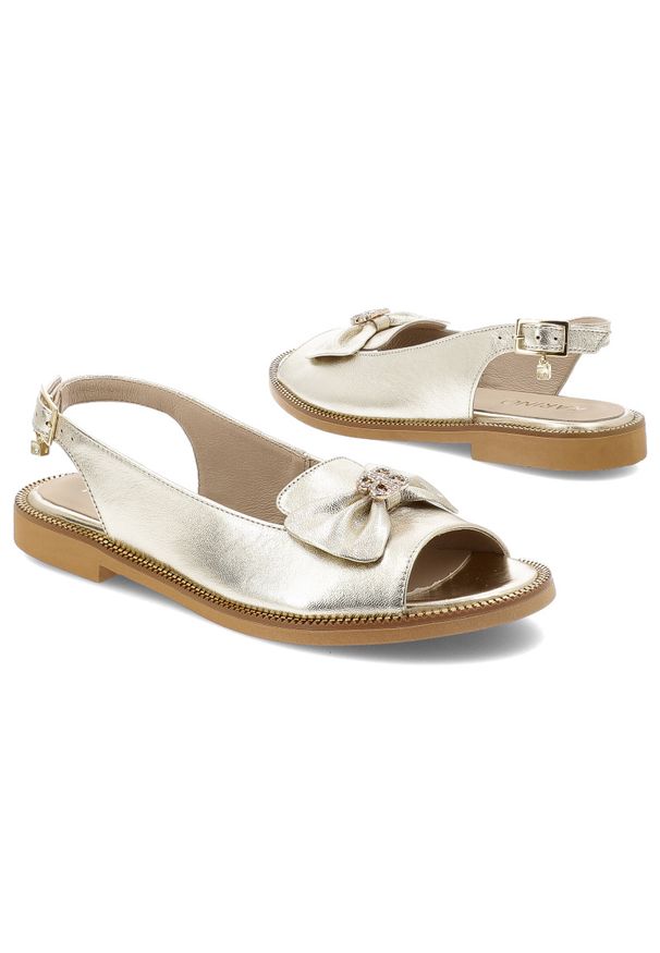 Złote Sandały Karino Modne Obuwie Damskie Z Broszką. Nosek buta: otwarty. Zapięcie: pasek. Kolor: złoty. Materiał: skóra. Wzór: aplikacja. Sezon: lato. Obcas: na płaskiej podeszwie. Styl: elegancki, klasyczny