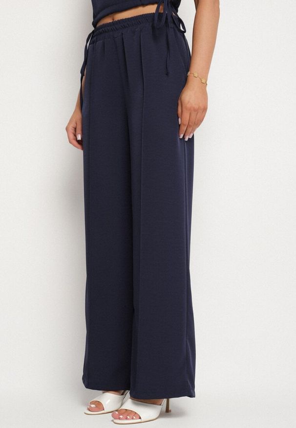 Born2be - Granatowy Komplet Kopertowa Bluzka z Kwiatową Broszką i Szerokie Spodnie Reavilia. Kolor: niebieski. Wzór: kwiaty