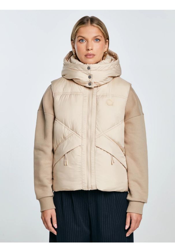 Big-Star - Kamizelka damska pikowana z kapturem beżowa Enifata 801. Typ kołnierza: kaptur. Kolor: beżowy. Materiał: tkanina, materiał. Wzór: geometria, aplikacja. Styl: sportowy