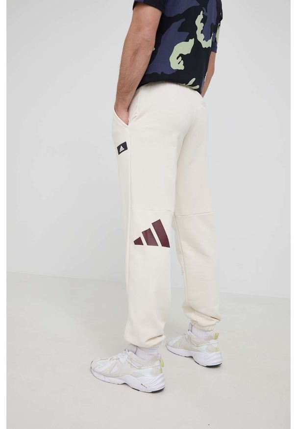 adidas Performance spodnie męskie kolor beżowy z nadrukiem. Kolor: beżowy. Materiał: materiał, dzianina. Wzór: nadruk