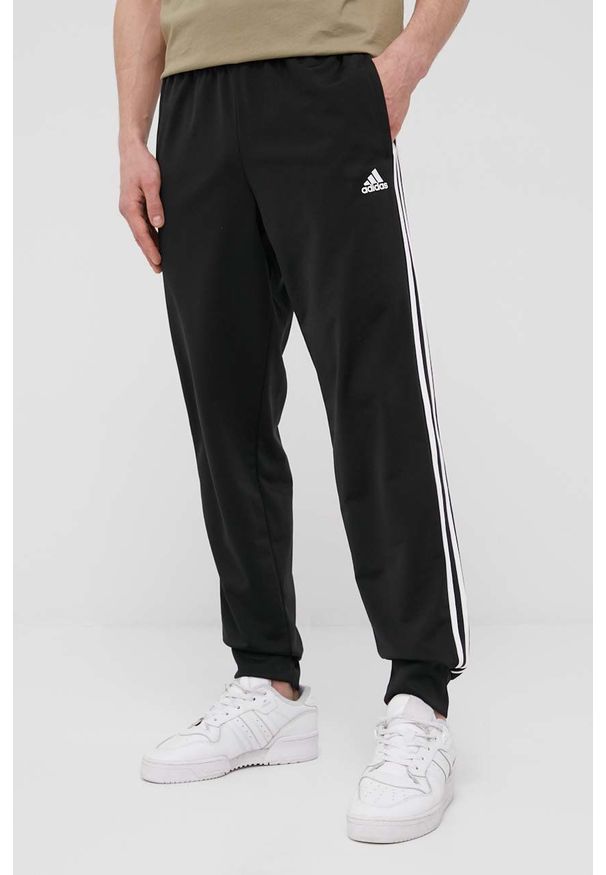 Adidas - adidas spodnie męskie kolor czarny z aplikacją. Kolor: czarny. Materiał: poliester, materiał. Wzór: aplikacja