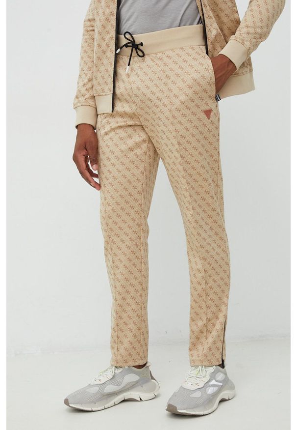 Guess spodnie dresowe męskie kolor beżowy wzorzyste. Kolor: beżowy. Materiał: dresówka