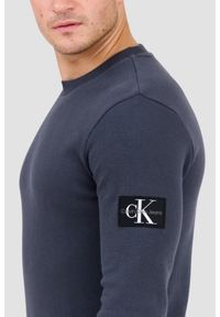 Calvin Klein - CALVIN KLEIN Szary męski longsleeve z naszywką. Okazja: na co dzień. Kolor: szary. Materiał: bawełna. Długość rękawa: długi rękaw. Wzór: aplikacja. Styl: casual, klasyczny