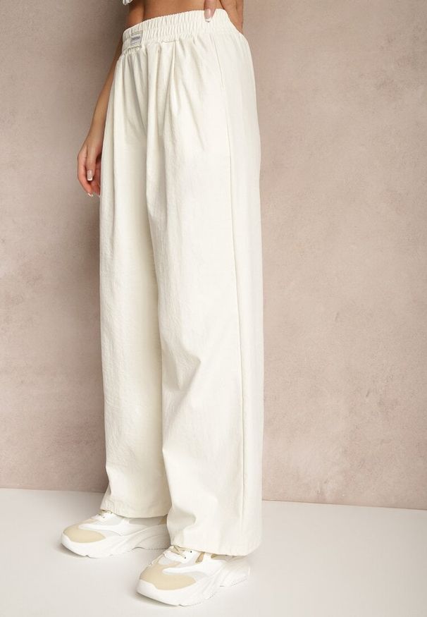 Renee - Jasnobeżowe Spodnie o Szerokim Kroju z Bawełną High Waist Ozdobione Naszywką Naneriela. Okazja: na co dzień. Stan: podwyższony. Kolor: beżowy. Materiał: bawełna. Wzór: aplikacja. Styl: casual, elegancki