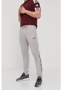 Adidas - adidas Spodnie męskie kolor szary z nadrukiem. Kolor: szary. Materiał: poliester, dzianina. Wzór: nadruk