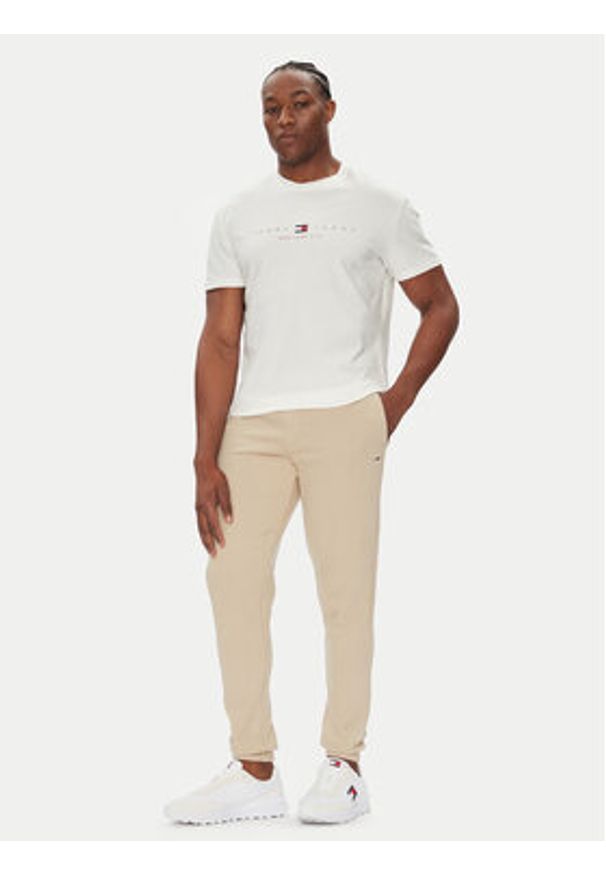 Tommy Jeans Spodnie dresowe Flag DM0DM20473 Beżowy Slim Fit. Kolor: beżowy. Materiał: bawełna