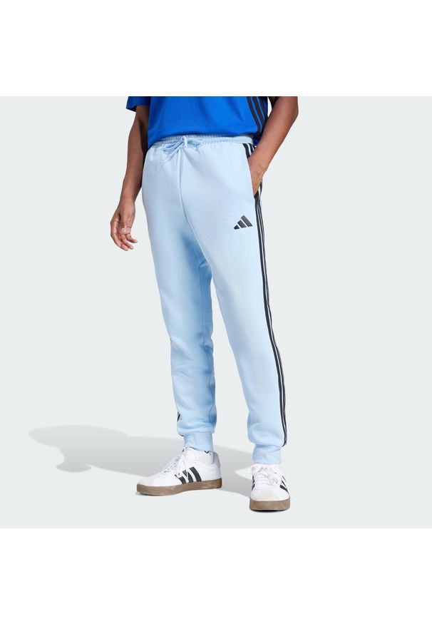 Adidas - Spodnie Essentials 3-Stripes Fleece. Kolor: wielokolorowy, niebieski, czarny. Materiał: polar, materiał. Sport: fitness
