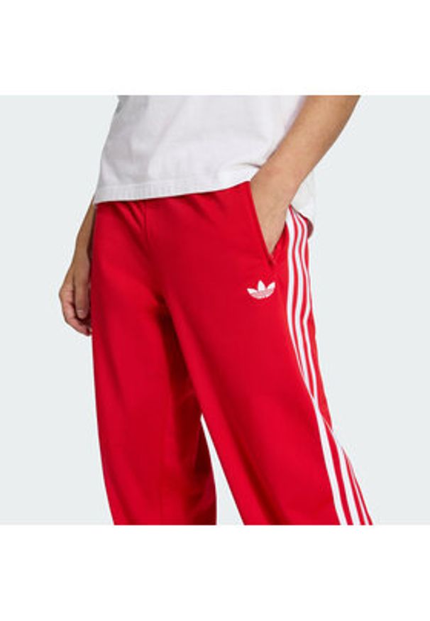 Adidas - adidas Spodnie dresowe Firebird KD8319 Czerwony Loose Fit. Kolor: czerwony. Materiał: syntetyk