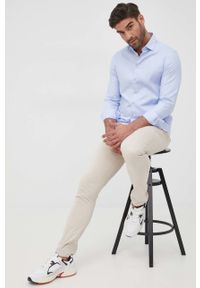 Calvin Klein spodnie męskie kolor beżowy w fasonie chinos. Kolor: beżowy. Materiał: materiał, bawełna, dzianina. Wzór: gładki