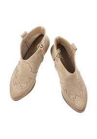 Botki damskie Armodo, cholewka ze skóry naturalnej zamszowej z dekoracyjnym przeszyciem inspirowanym stylem western, stabilny obcas o średniej wysoko. Zapięcie: zamek. Kolor: beżowy. Materiał: zamsz, skóra. Szerokość cholewki: normalna. Obcas: na obcasie. Wysokość obcasa: średni #2