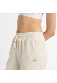 Spodnie damskie New Balance WP51503LIN – beżowe. Kolor: beżowy. Materiał: bawełna, poliester. Wzór: haft, aplikacja #2