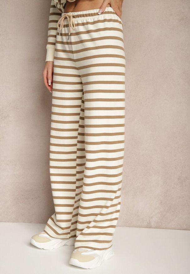 Renee - Beżowe Szerokie Spodnie Dresowe z Bawełną Ozdobione Paskami i Sznurkami Fenilira. Okazja: na co dzień. Stan: podwyższony. Kolor: beżowy. Materiał: dresówka, bawełna. Wzór: aplikacja. Styl: casual