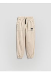 Reserved - Joggery z efektem sprania - kremowy. Kolor: kremowy. Materiał: dzianina, bawełna