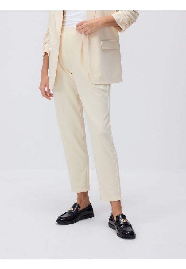 Reserved - Spodnie jogger z zakładkami - jasnożółty. Kolor: żółty. Materiał: dzianina