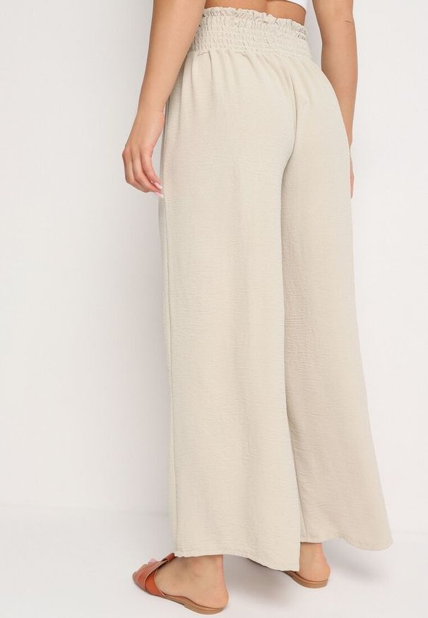 Born2be - Beżowe Szerokie Spodnie z Wysokim Stanem Wykończone Gumką w Pasie Risinassa. Okazja: na spotkanie biznesowe. Stan: podwyższony. Kolor: beżowy. Styl: biznesowy