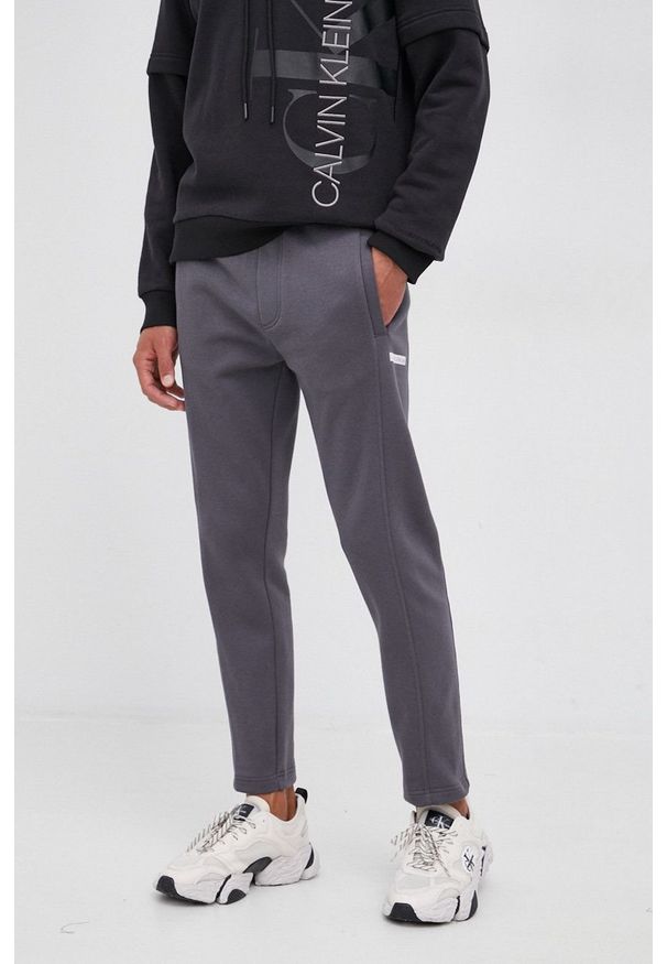 Calvin Klein Jeans Spodnie męskie kolor szary gładkie. Kolor: szary. Materiał: bawełna, włókno, dzianina. Wzór: gładki