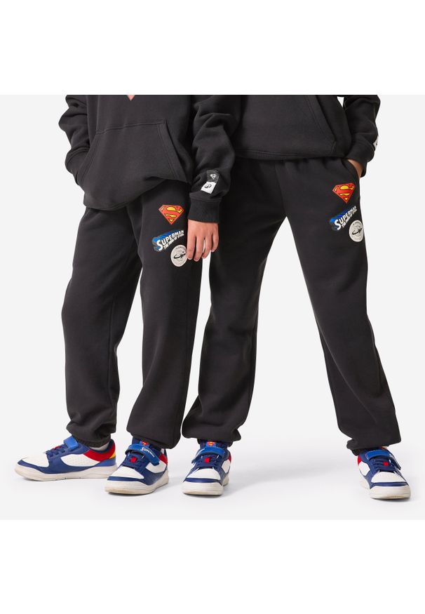 Decathlon - Spodnie dla dzieci Domyos Superman. Kolor: czarny. Materiał: materiał, poliester, bawełna. Wzór: motyw z bajki. Sport: fitness, joga i pilates
