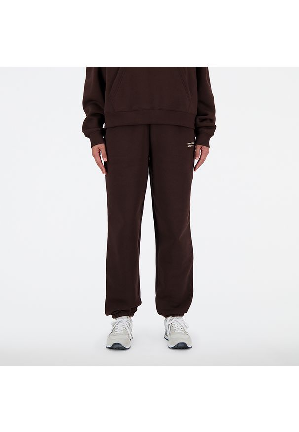 Spodnie damskie New Balance WP33513KCF – brązowe. Stan: podwyższony. Kolor: brązowy. Materiał: poliester, prążkowany, dresówka, bawełna