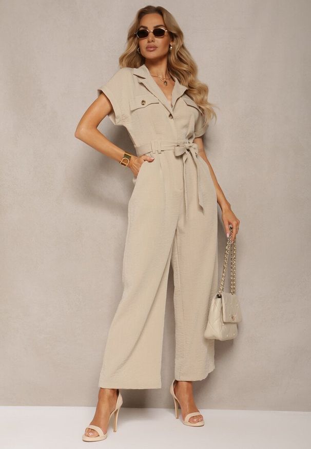 Renee - Beżowy Kombinezon z Długimi Nogawkami i Krótkim Rękawem z Guzikami i Paskiem Jolmeria. Kolor: beżowy. Długość rękawa: krótki rękaw. Długość: krótkie