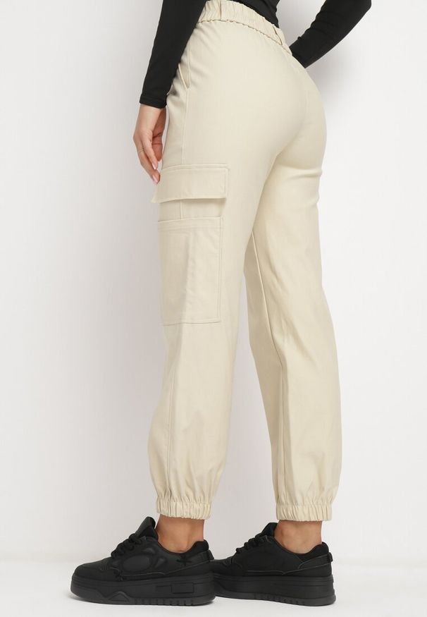 Born2be - Jasnobeżowe Spodnie Bojówki z Gumka w Pasie i na Dole przy Nogawkach Ozdobione Kieszenią z Klapą Veralie. Okazja: na co dzień. Kolor: beżowy. Materiał: bawełna. Wzór: aplikacja. Styl: klasyczny, casual, militarny, elegancki