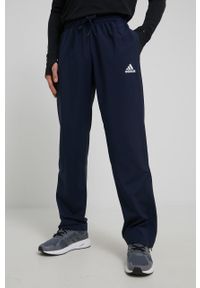 Adidas - adidas spodnie męskie kolor granatowy z nadrukiem. Kolor: niebieski. Materiał: materiał, poliester, skóra. Wzór: nadruk. Sport: fitness