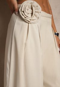Renee - Beżowe Spodnie o Szerokim Kroju High Waist z Kwiatem 3D Firalisse. Okazja: na co dzień. Stan: podwyższony. Kolor: beżowy. Wzór: kwiaty. Styl: klasyczny, elegancki, casual