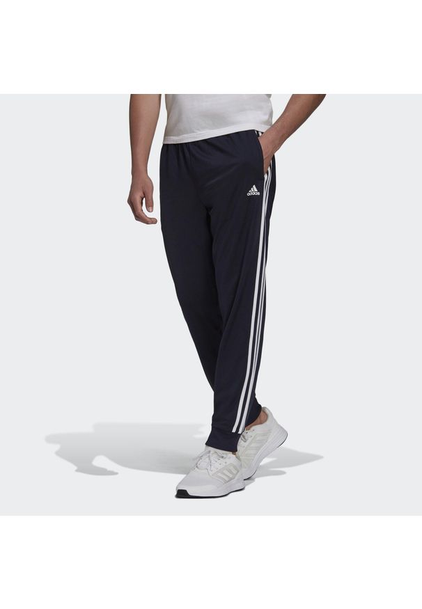 Adidas - Primegreen Essentials Warm-Up Tapered 3-Stripes Track Pants. Kolor: czarny, biały, niebieski, wielokolorowy. Materiał: poliester, dresówka, materiał. Sport: fitness