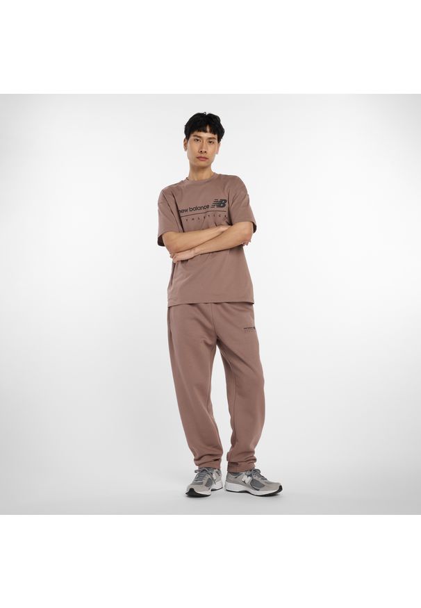 Spodnie męskie New Balance MP53508EAS – brązowe. Kolor: brązowy. Materiał: dresówka, poliester, bawełna, materiał. Wzór: aplikacja, napisy
