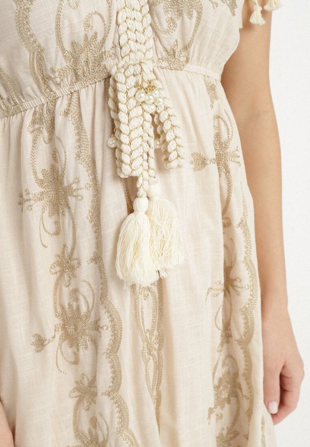 Born2be - Beżowa Bawełniana Sukienka w Boho Print Rozkloszowana z Metalicznymi Haftami i Frędzlami Divilea. Okazja: na co dzień. Typ kołnierza: dekolt w kształcie V. Kolor: beżowy. Materiał: bawełna. Długość rękawa: długi rękaw. Wzór: nadruk, haft. Styl: boho